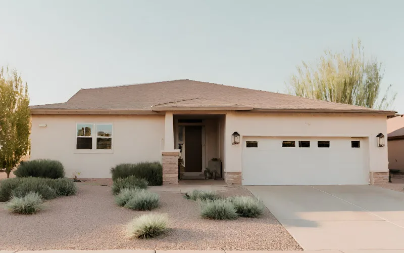 Single-story beige house with stone accents and garage, surrounded by desert landscaping in Buckeye, Arizona.