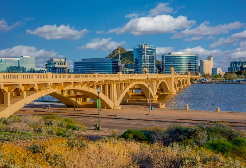 Bridge over water with high-rise buildings and mountains, representing Pipeliners USA's modern plumbing solutions in Tempe.