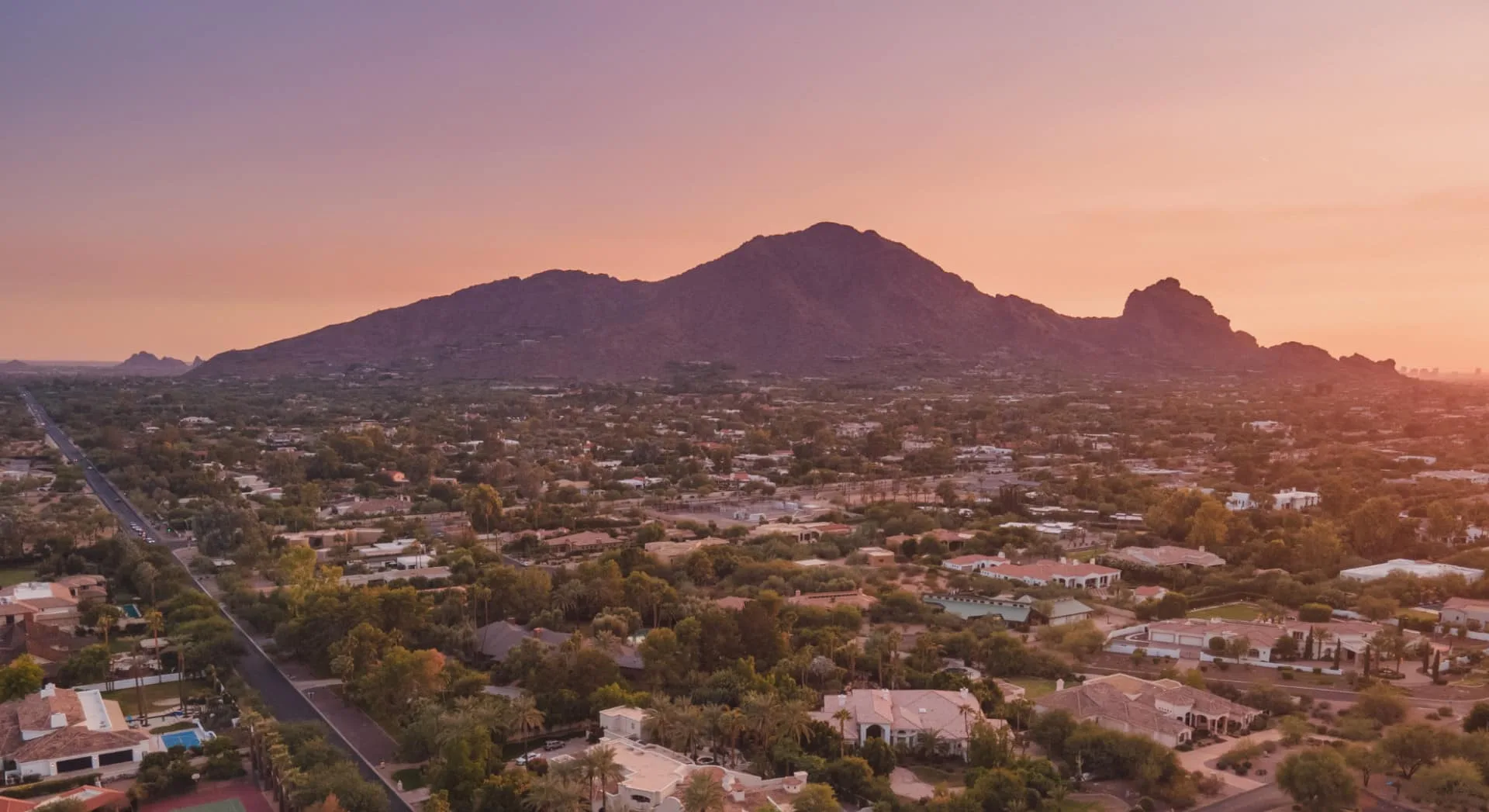 Sunset over residential areas in Laveen with mountains, reflecting Pipeliners USA's eco-friendly pipe repair services.