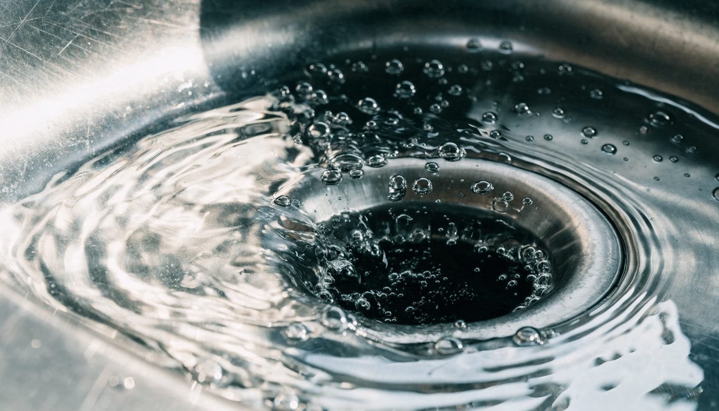 Water draining slowly at a kitchen sink, a sign of a restricted sewer line